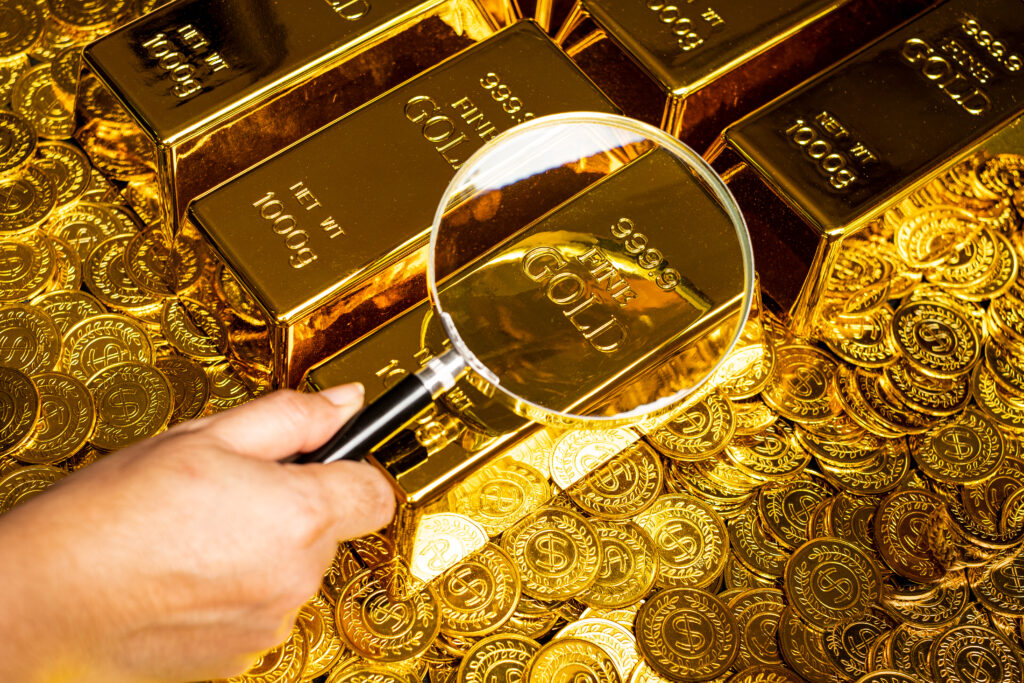 a-hand-with-a-magnifying-glass-checks-the-gold-bar